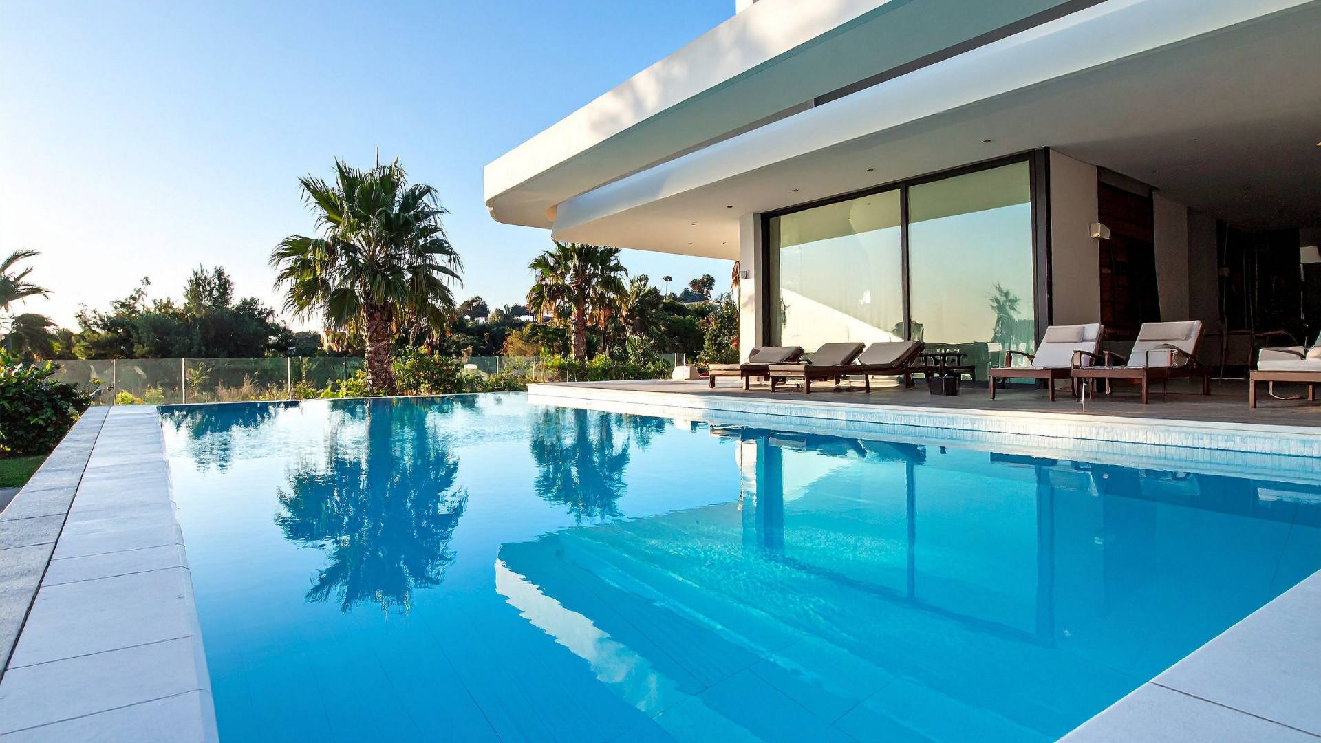 Infinity-edge vinyl pool with palm trees and lounge seating